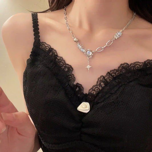 Person, die ein schwarzes Spitzenoberteil mit einer silbernen Halskette mit einem Sternanhänger trägt.