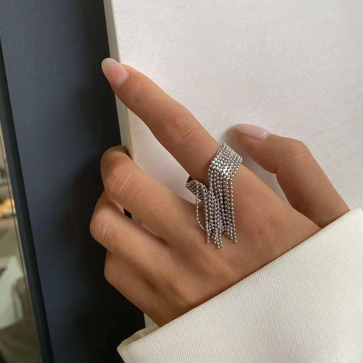 Die Hand einer Frau, die einen vergoldeten Edelstahlring mit 18-karätiger Goldbeschichtung und einer mehrschichtigen Perlenquaste trägt.