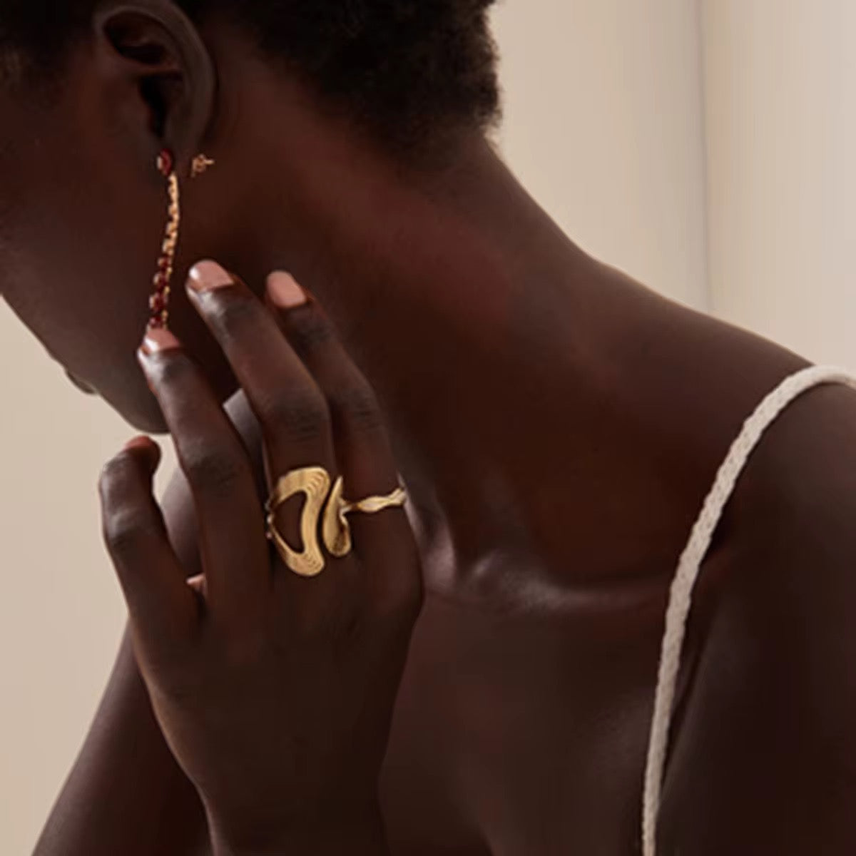 Eine Person, die einen vergoldeten Edelstahlring mit einem Wellenmuster am Finger trägt.