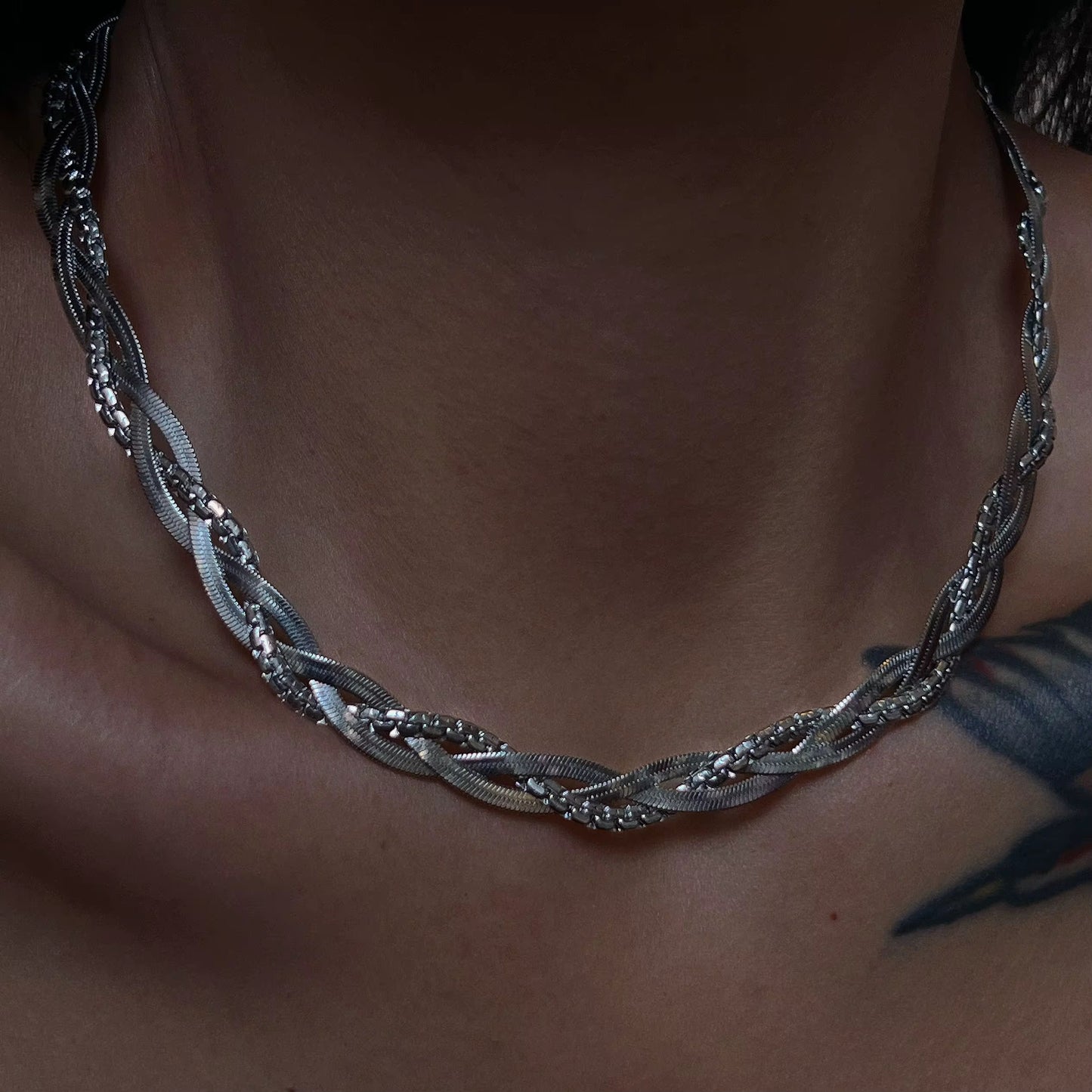 Nahaufnahme einer versilberten Edelstahlkette mit Bambusdesign, die von einer Person getragen wird.